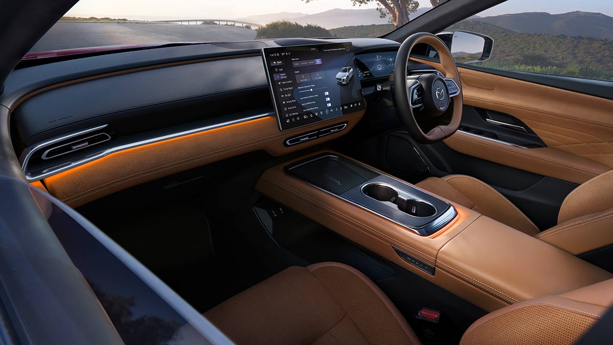Mazda 6e parked at mountainous location with view from frameless doors into minimalist cockpit with tan leather.