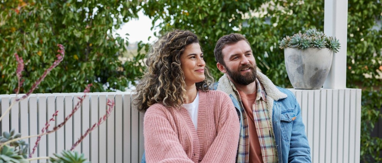 A couple sitting together outside with a drink each
