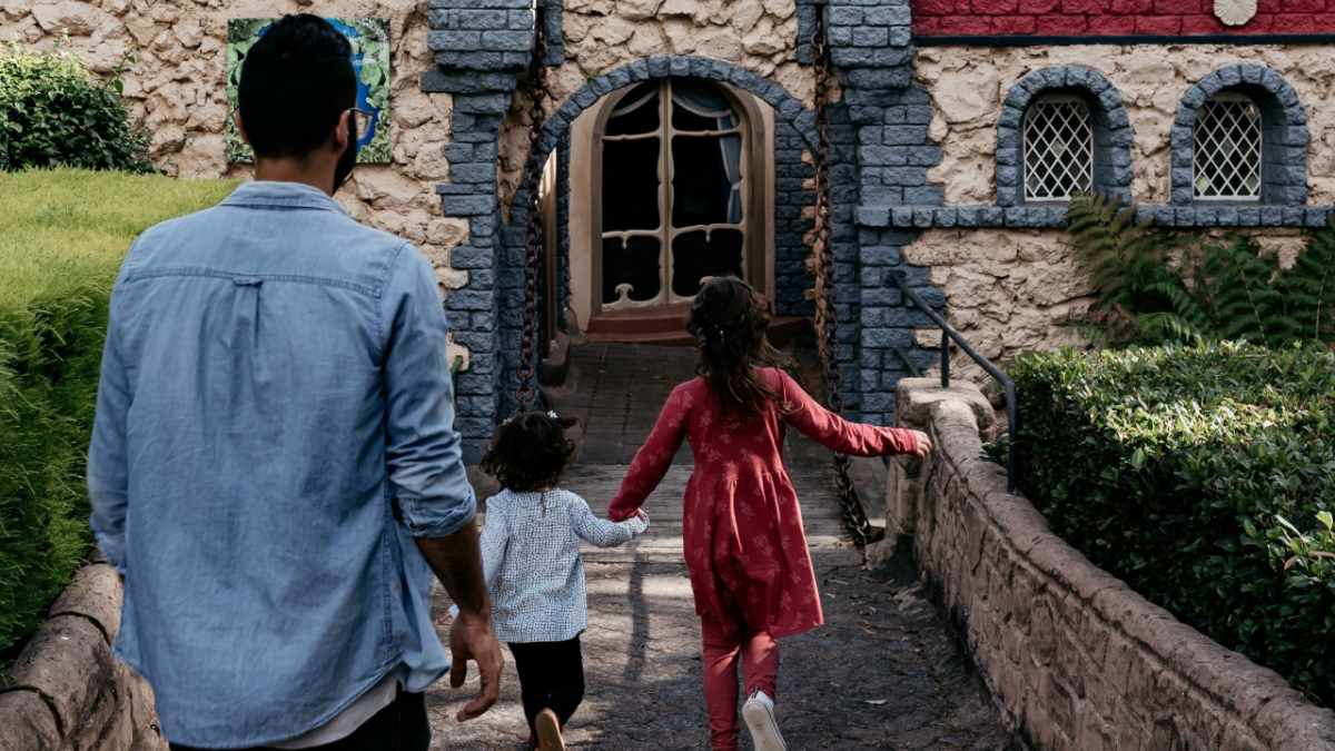 man and two daughters walking into Fairy Park