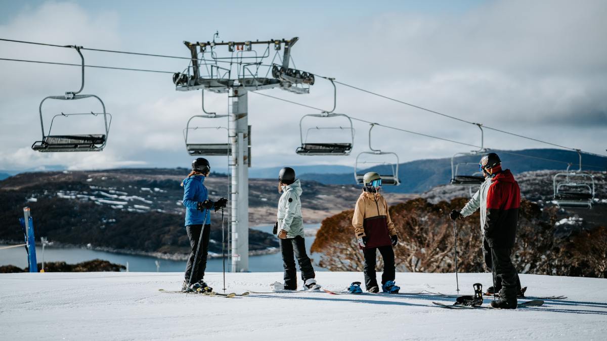 four friends on skis standing under chair lift at Falls Creek, Victoria