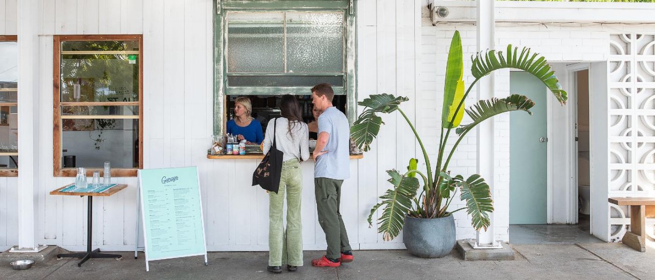 man and woman ordering coffee from whitewashed building