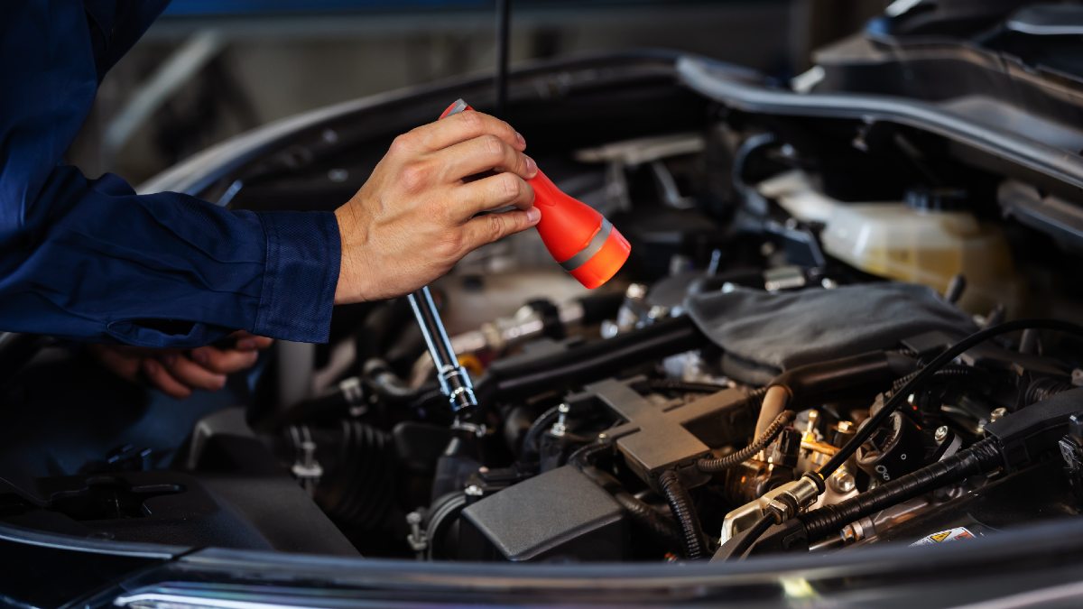man's hand holding torch to see into car bonnet
