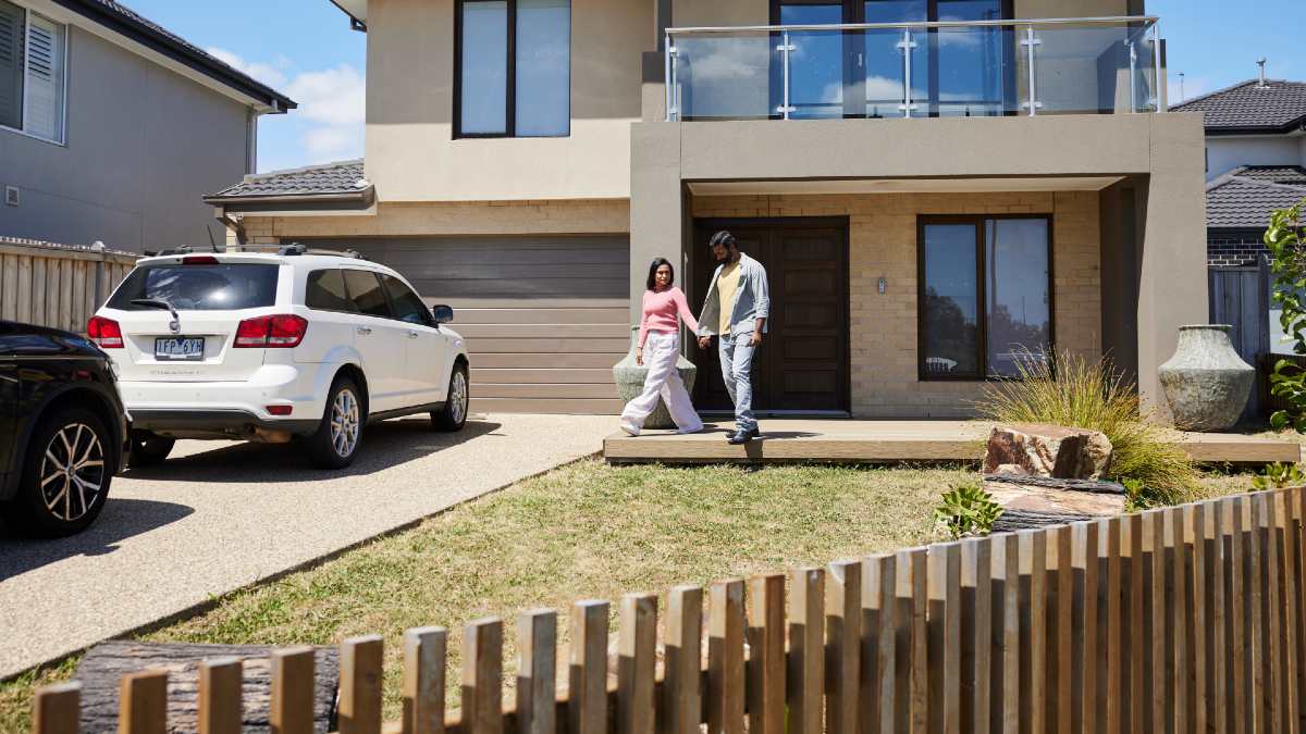 young couple walking out the front of their house