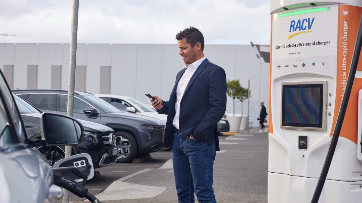 man looking at his smartphone next to an RACV Chargefox EV charger