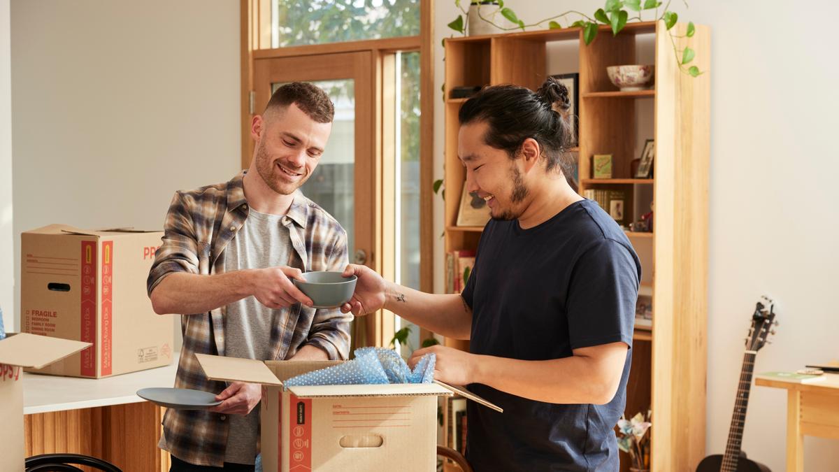 two young men unpacking boxes in their new home
