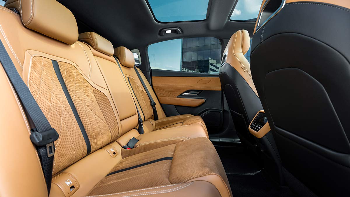 Rear seat area of Mazda 6e with quilted tan leather seat trim and panoramic sunroof.
