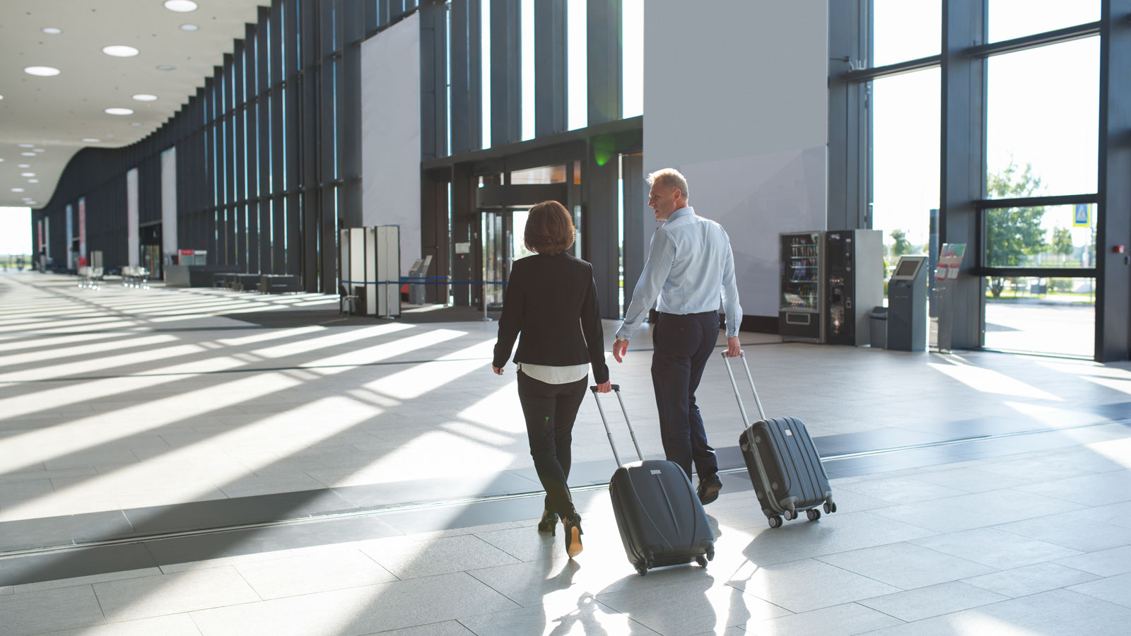 Couple rolling their carry on suitcases in the airport. 