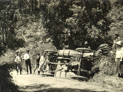 People standing beside a car rolled off the road during the Alpine Trial in 1921.