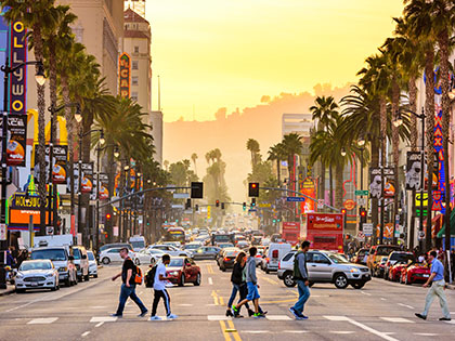 LOS ANGELES, CALIFORNIA - MARCH 1, 2016: Traffic and pedestrians on Hollywood Boulevard at dusk. The theater district is famous tourist attraction.