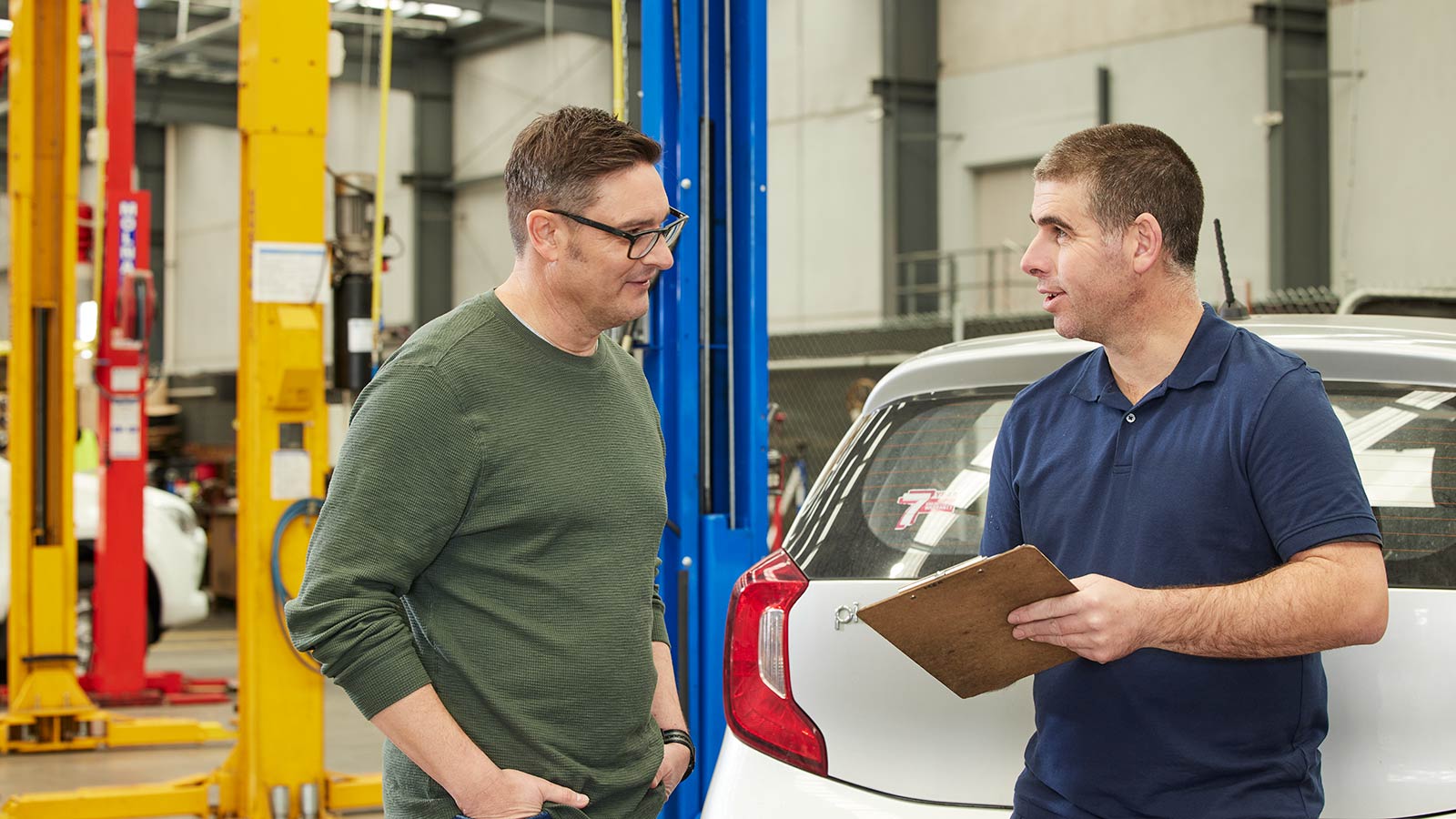 Mechanic talking to a customer in an auto repair shop.