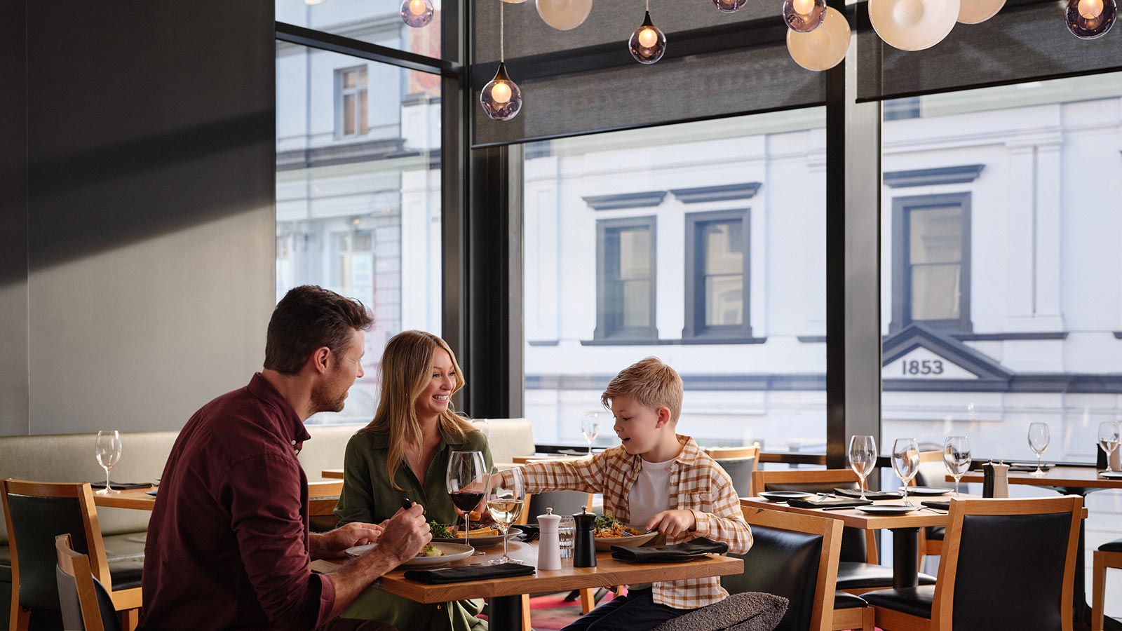 A family enjoying a meal at Hobart Hotel's Charcoal restaurant.