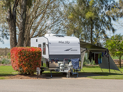 Caravan set up with a washing line next to greenery at RACV Cobram Resort's caravan site.