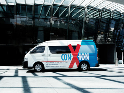 Con-X-Ion shuttle bus parked outside a building.