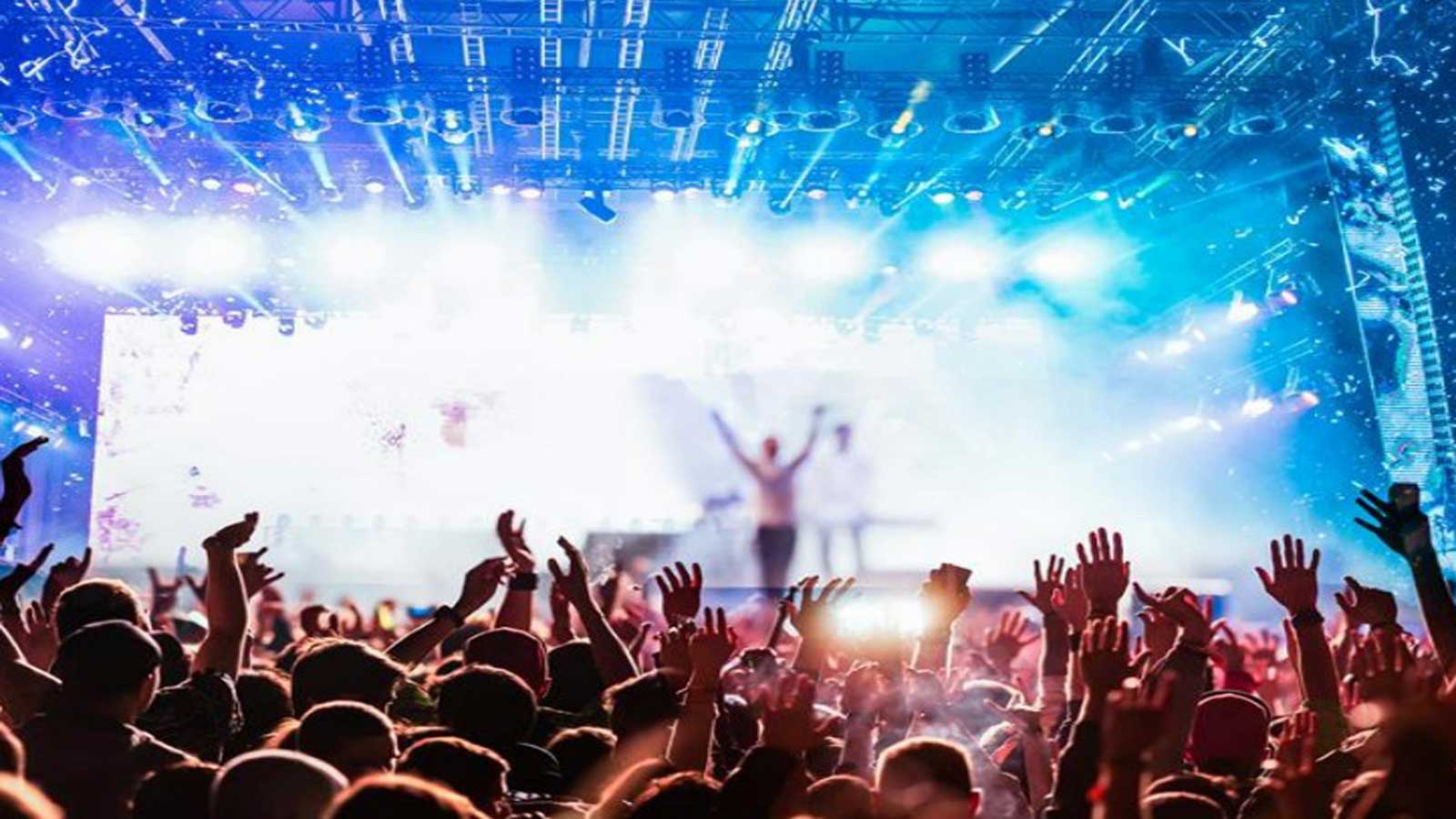 A large crowd at a concert with bright lighting. 