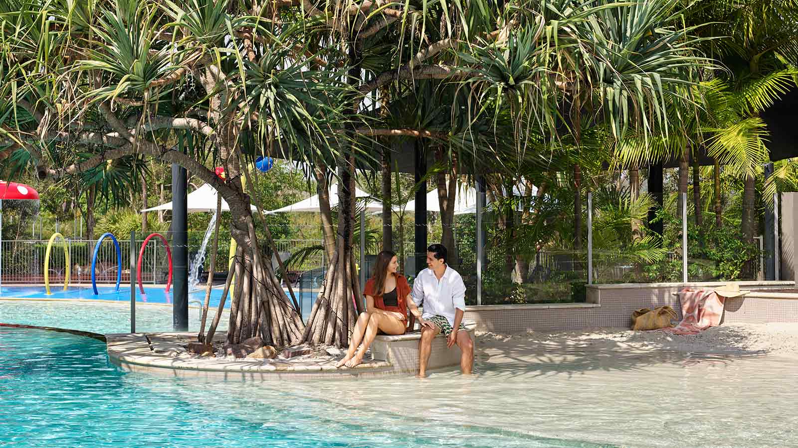 Couple sitting by outdoor pool at RACV Noosa Resort.