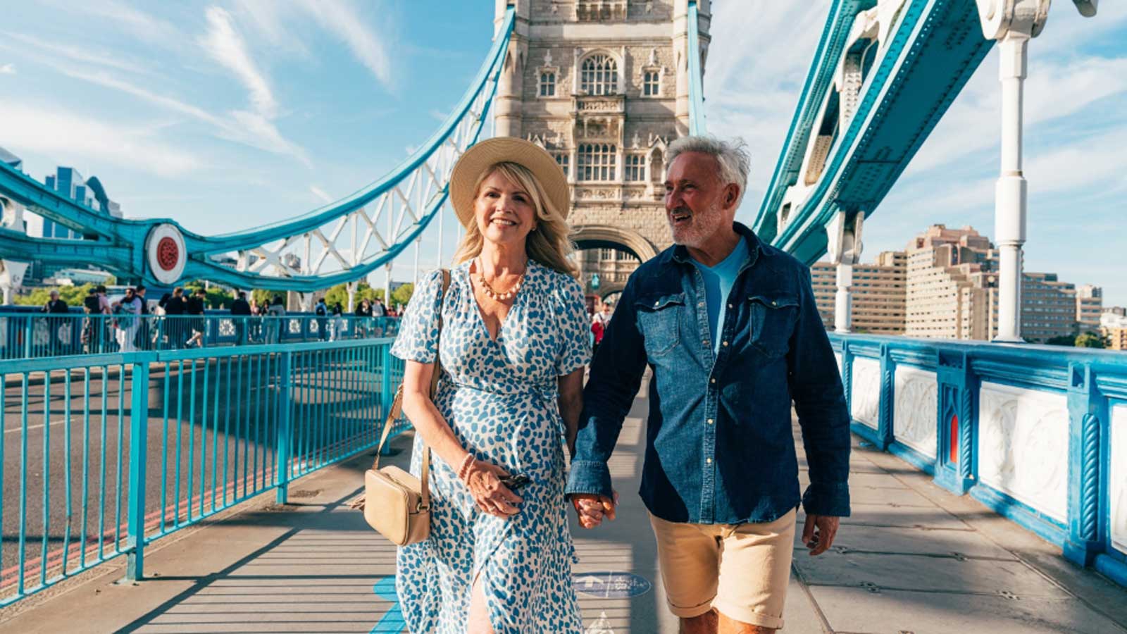 A couple walking hand in hand accross a bridge in London. 