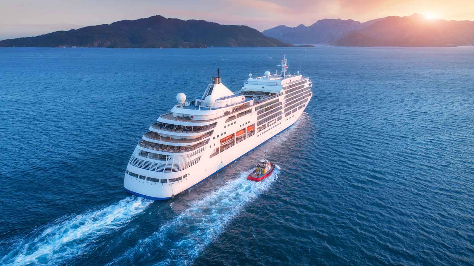Aerial view of a large white ship at sunset on the open ocean.