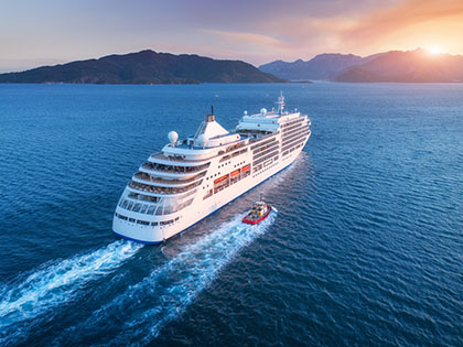 Aerial view of a large white ship at sunset on the open ocean.