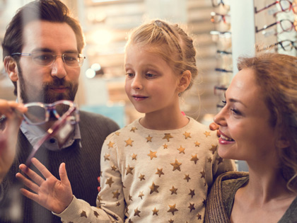 Mother and daughter trying on glasses with a retail worker