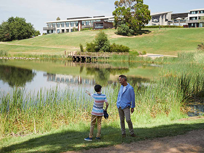 Adult and child looking and standing by lake at RACV Healesville Country Club and Resort.