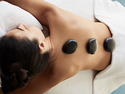 Person lying down with hot stones on their back at RACV Healesville Country Club and Resort's One Spa.