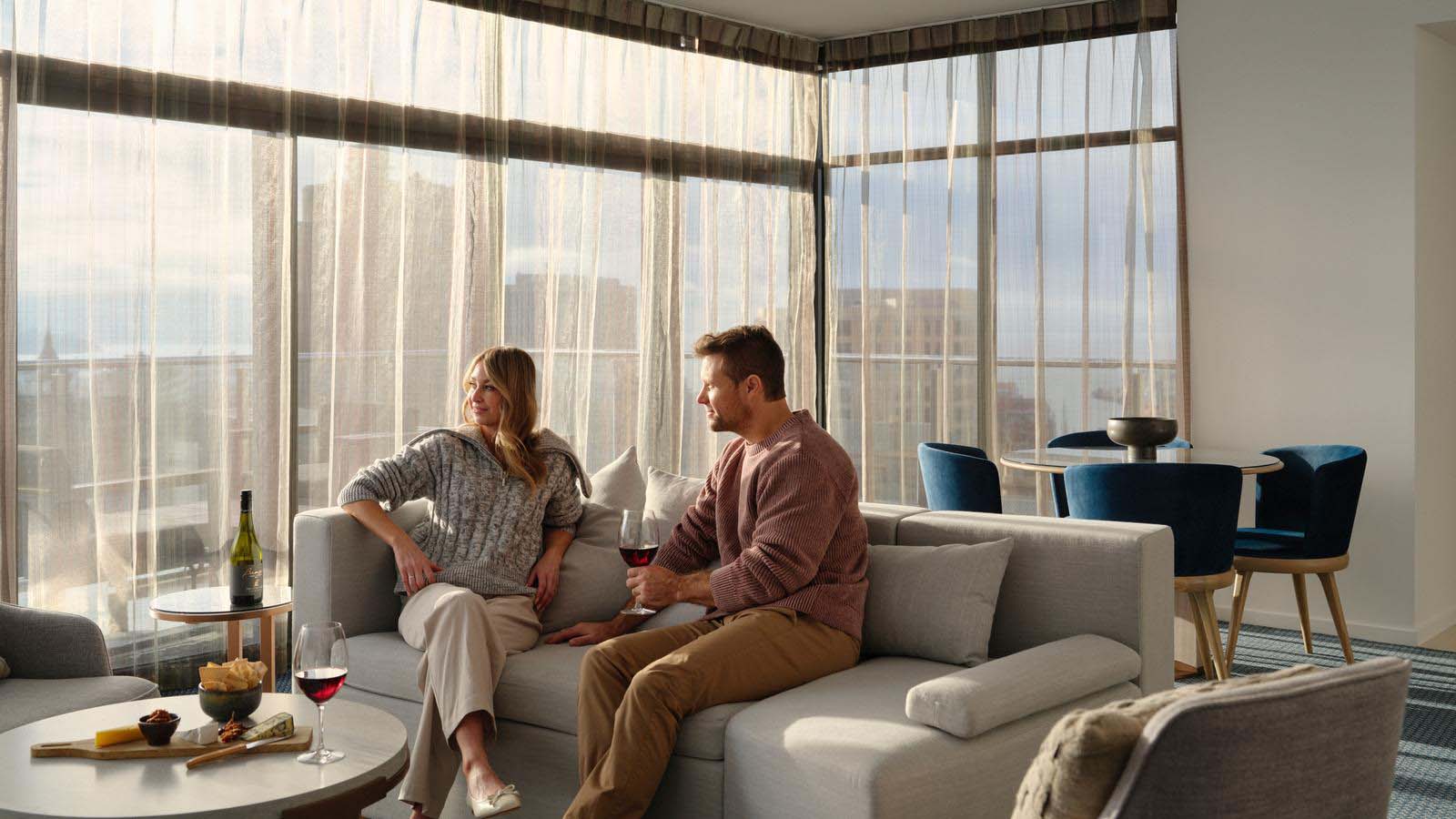 A couple enjoying a drink on the lounge of their penthouse room at the RACV Hobart Hotel.