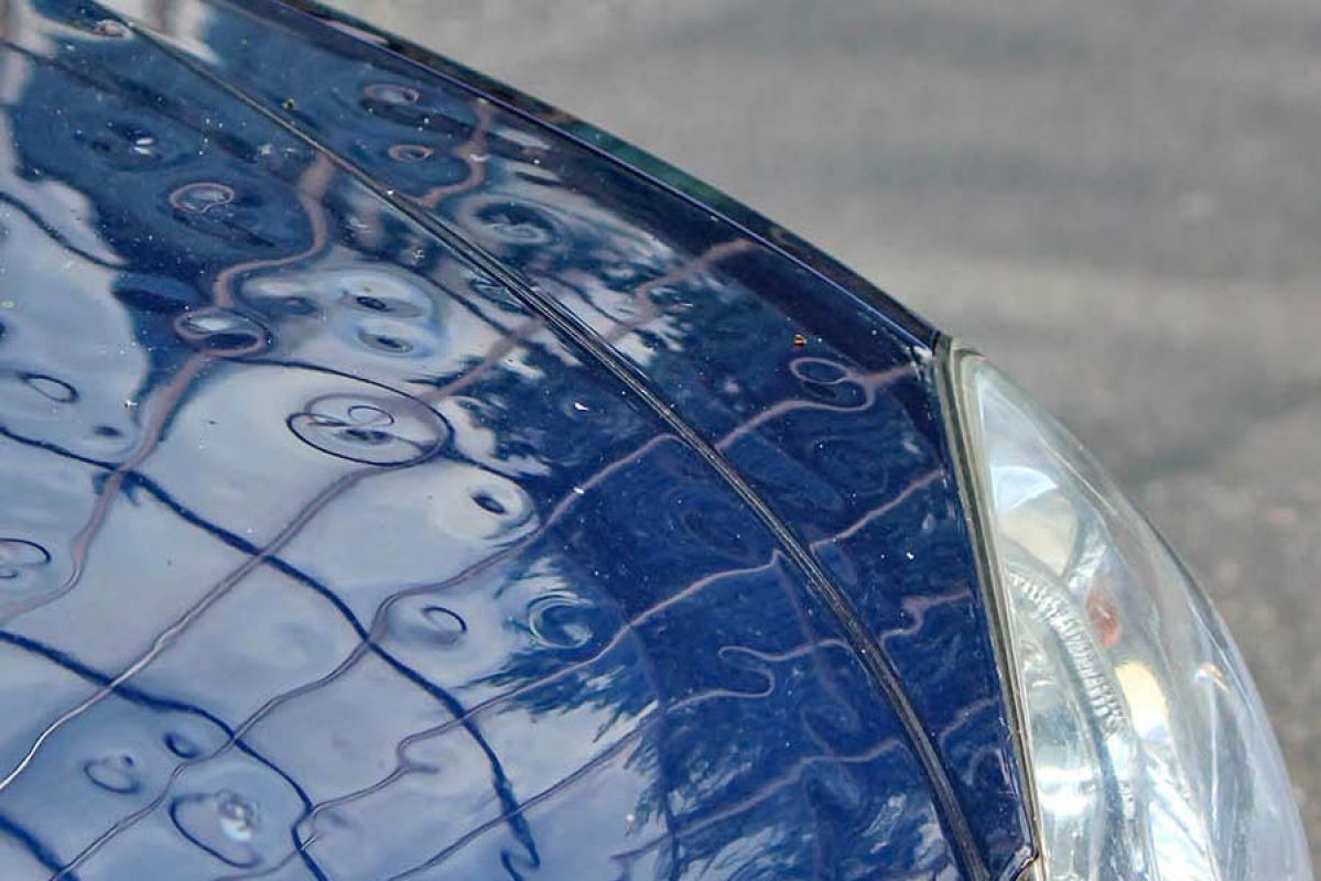Front of car with significant damage from hail