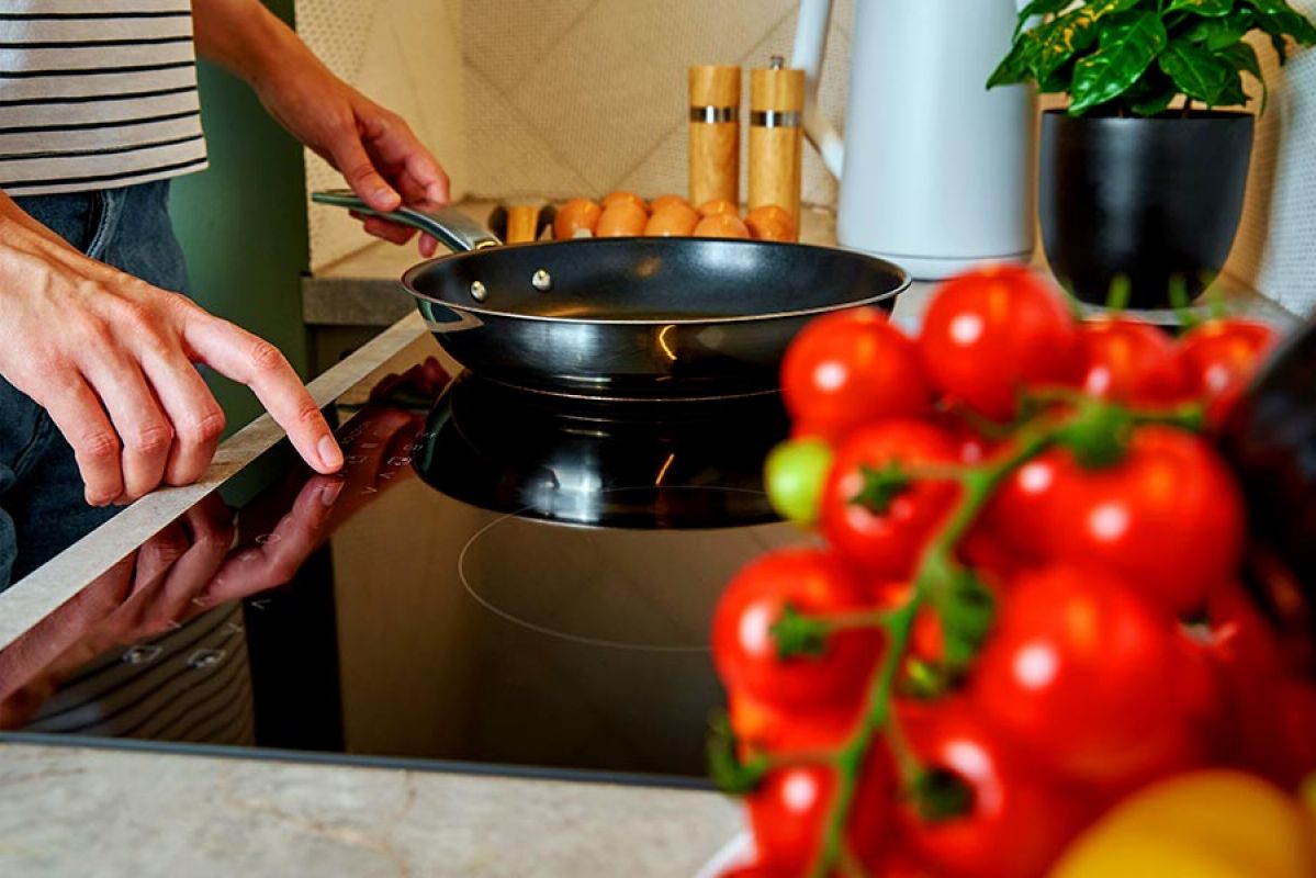 Overhead view of roof-mounted solar panels and woman in black swimsuit on deck at pool’s edge with another person diving into water
