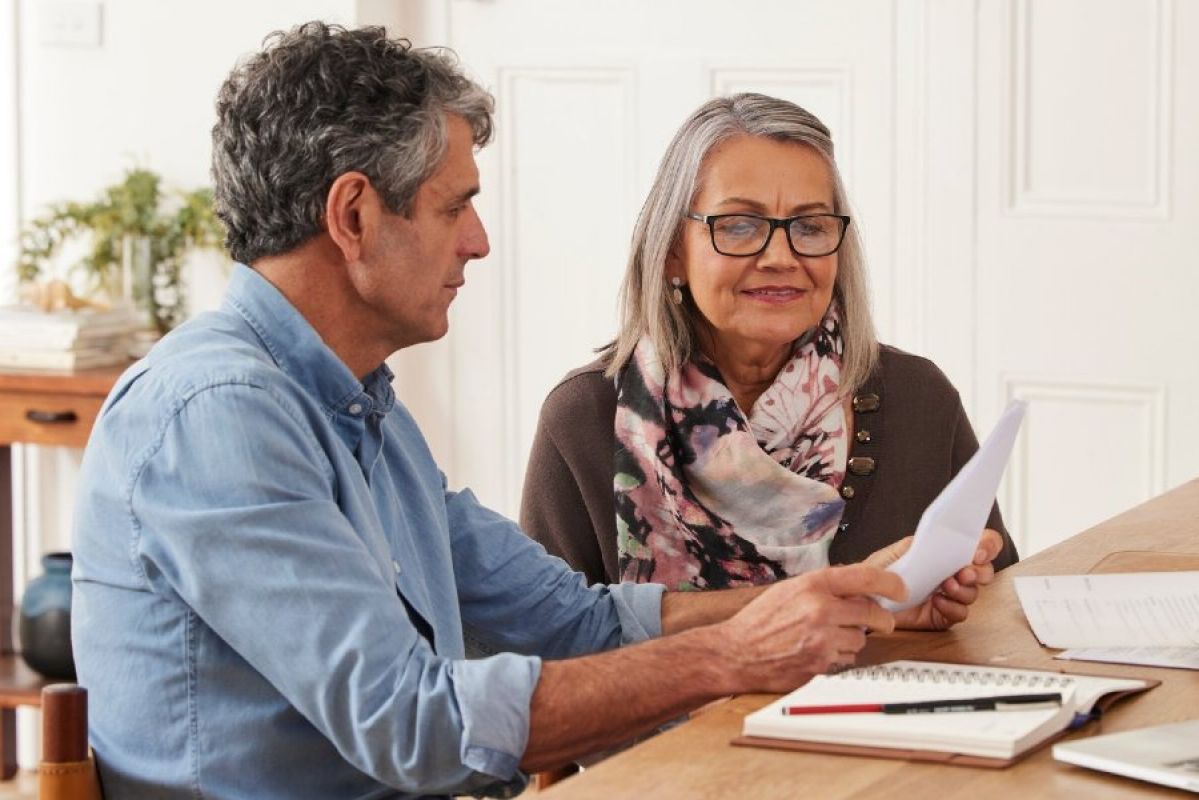 Two older people discuss documents