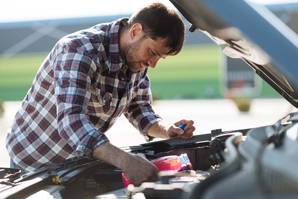 person pouring coolant into car's engine