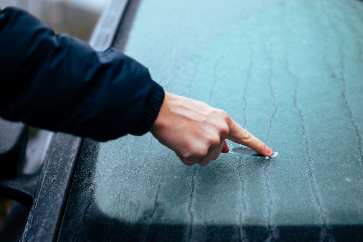 A person drags their finger across a frosty windscreen, demonstrating  how icy it is