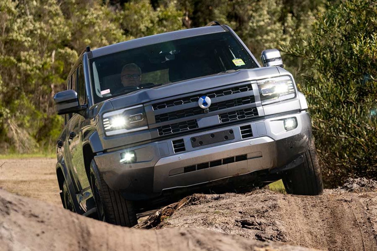 Grey Denza B5 SUV driving on steeply banked and rutted off-road course at Lang Lang proving ground in Victoria.