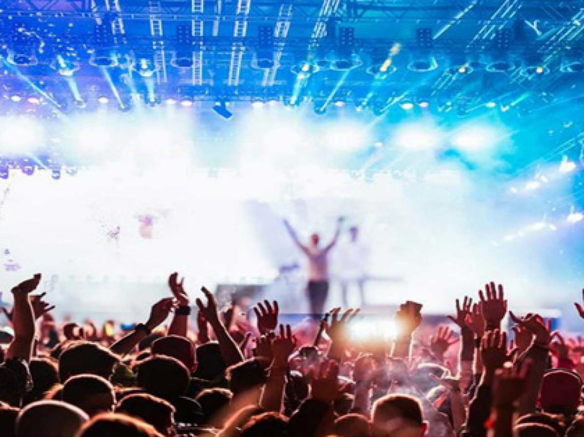 A large crowd at a concert with bright blue lights.