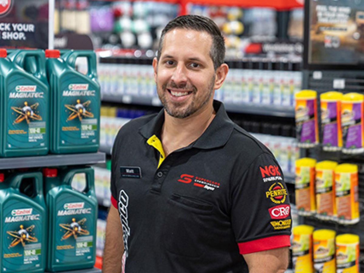 Repco staff member smiling at the camera infront of shelves.