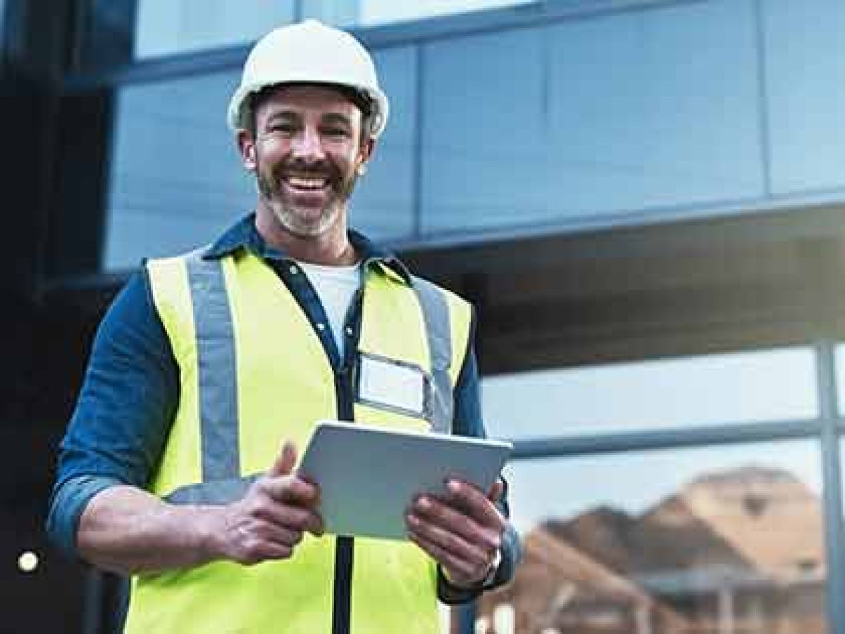Smiling man wearing a hard hat and hi-vis vest.