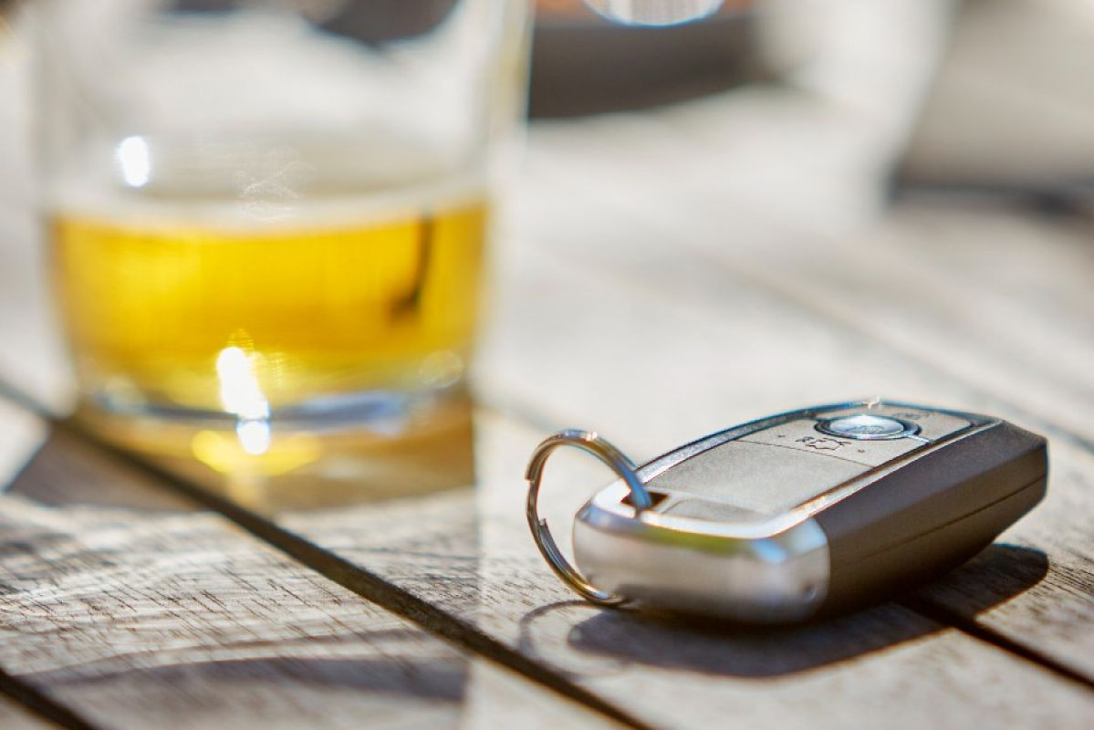 A car key fob on a table with  partly full glass of beer in the background