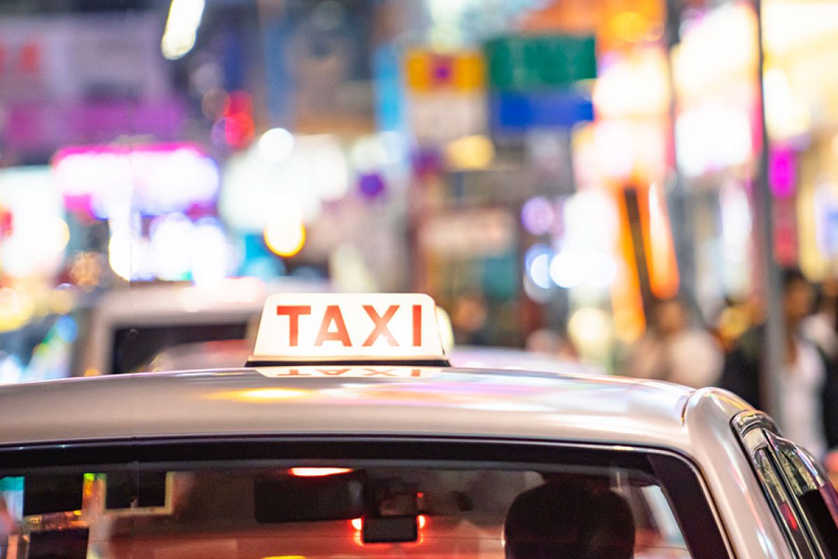 Boy sitting on suitcase at airport looking up at departures board
