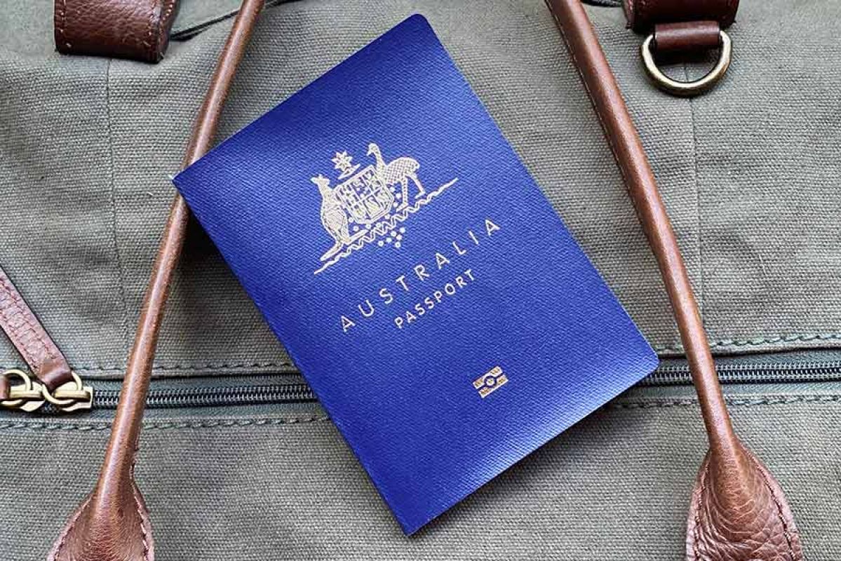 Blue Australian passport resting on green canvas travel bag with brown straps