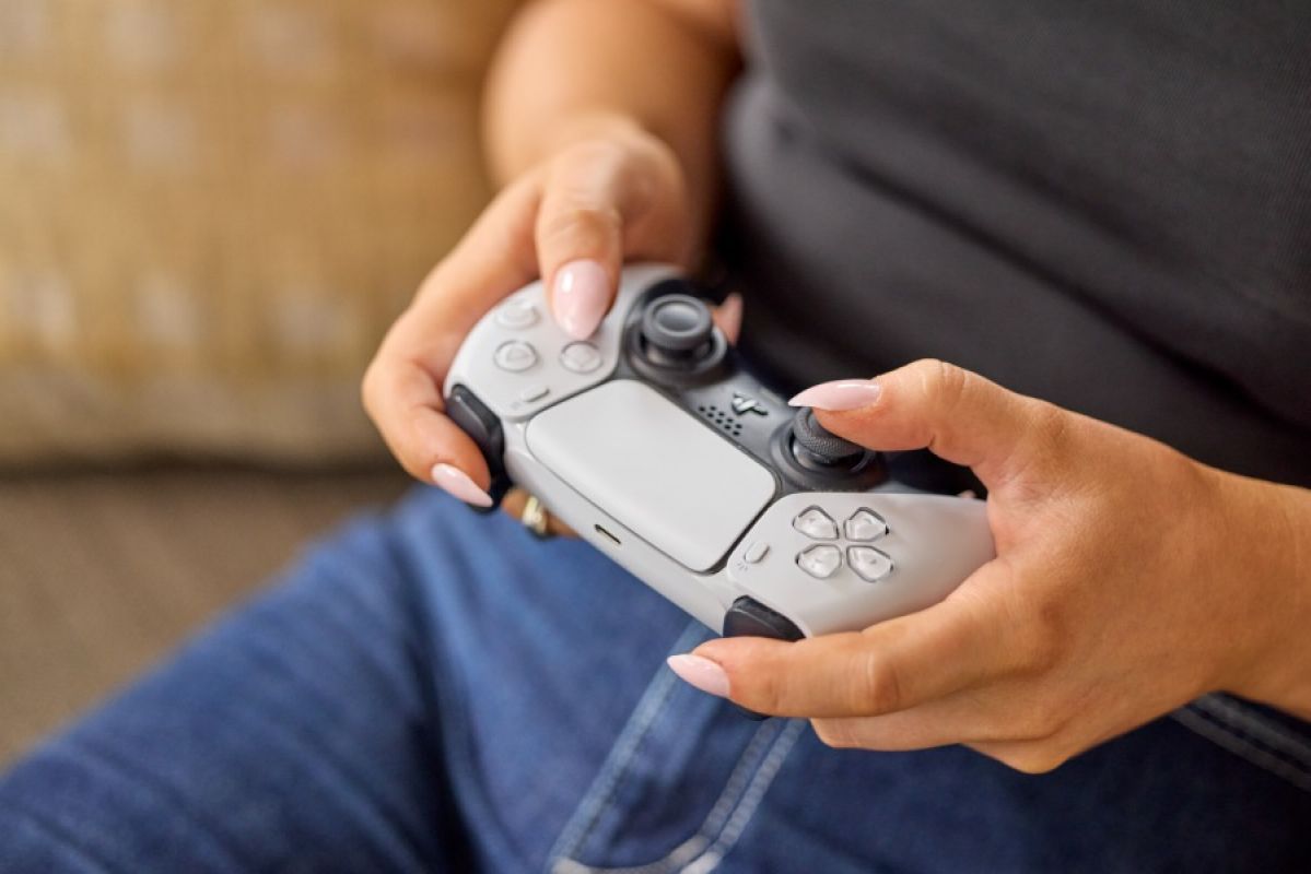 woman holding PS5 controller on couch