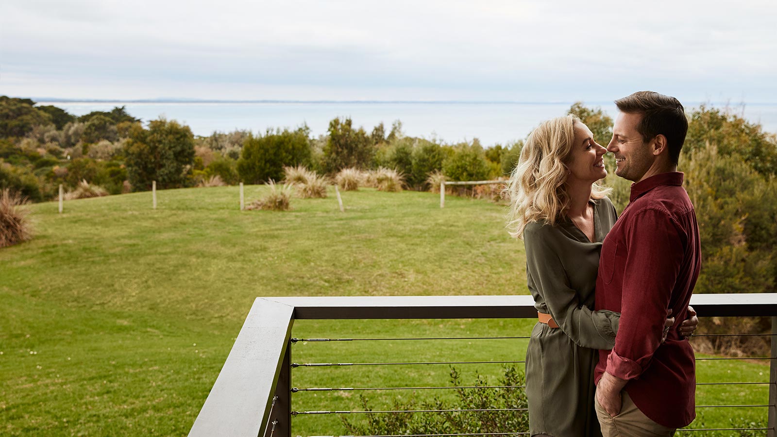 Couple hugging on a balcony overlooking the ocean at RACV Inverloch Resort.