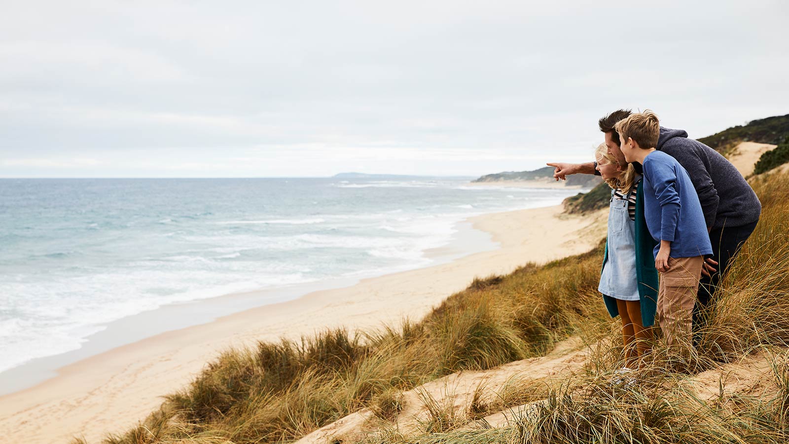 Parent and two kids standing together on the beach near RACV Inverloch Resort.