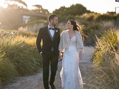 Bride and groom walking down an outdoor path outside RACV Inverloch Resort.