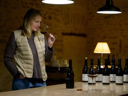 A woman smelling some red wine in a cellar. 