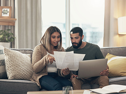 Couple sitting on couch looking at documents.
