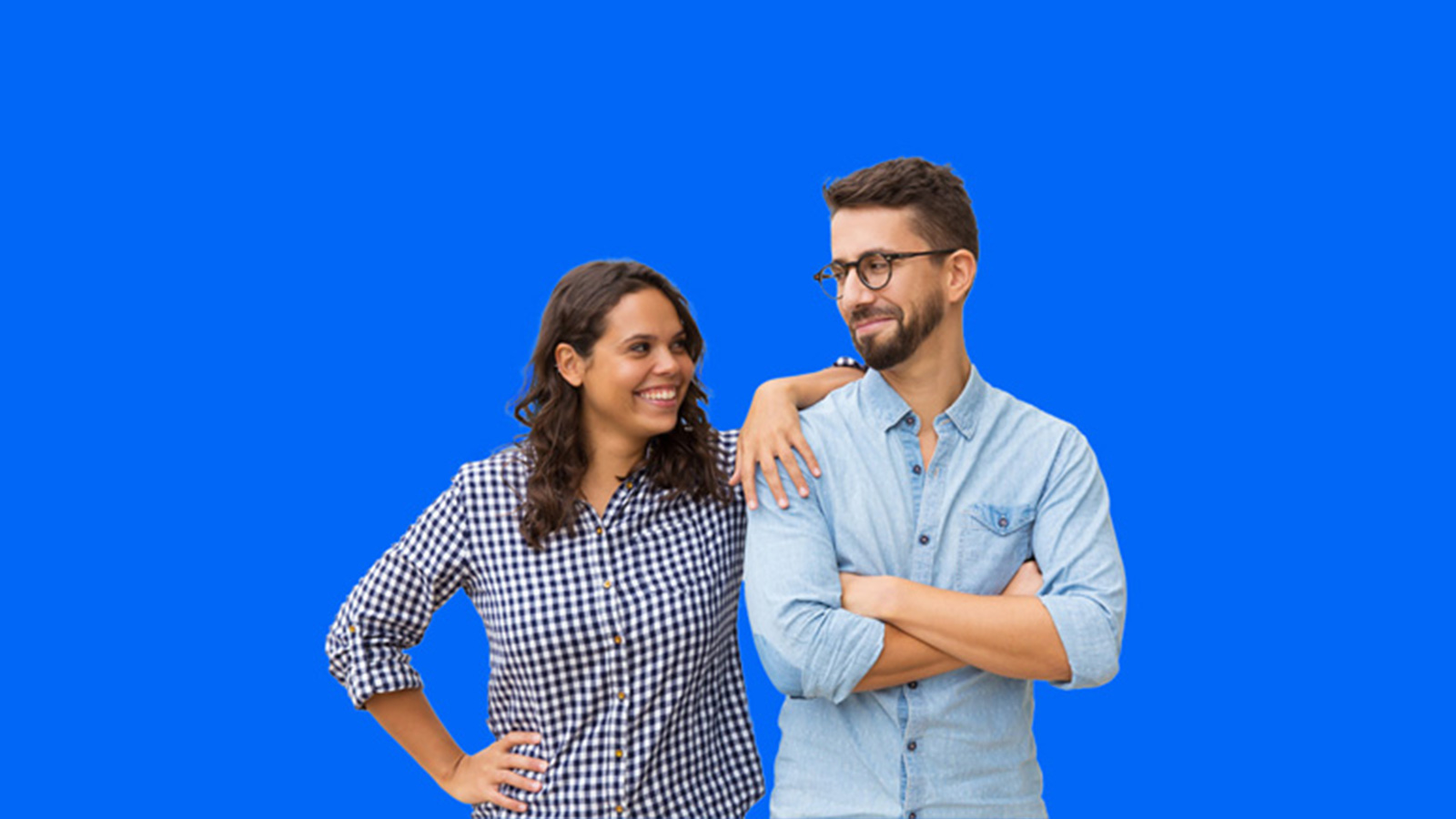 Man and woman smiling at each other on a blue backdrop.