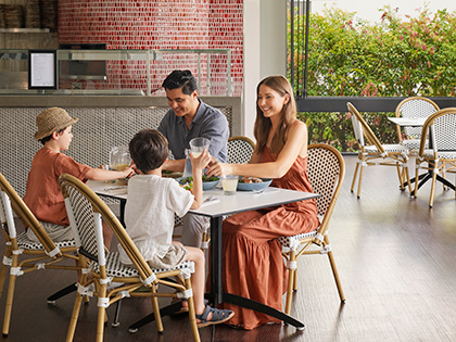 Parents and two children sitting and eating together at Dazza's Bar at RACV Noosa Resort.