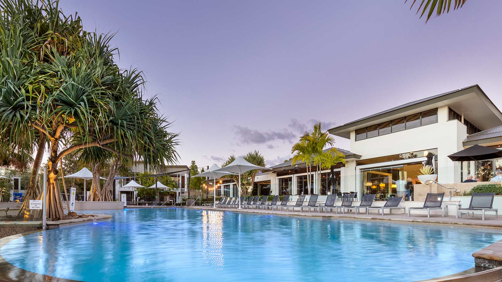 Outdoor pool at RACV Noosa Resort, with a row of pool chairs beside it.