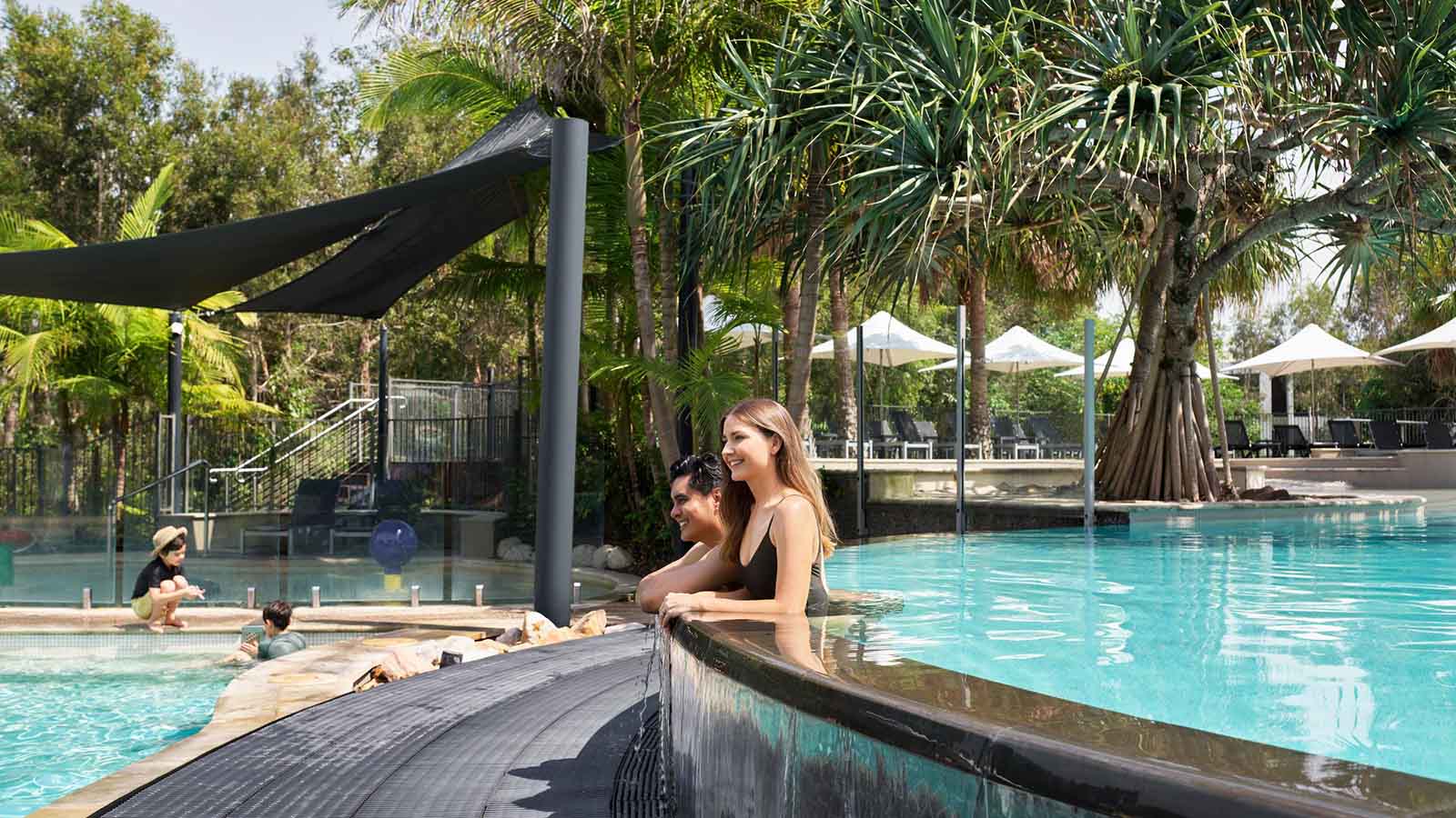 Two people leaning on the edge of the outdoor pool at RACV's Noosa resort.