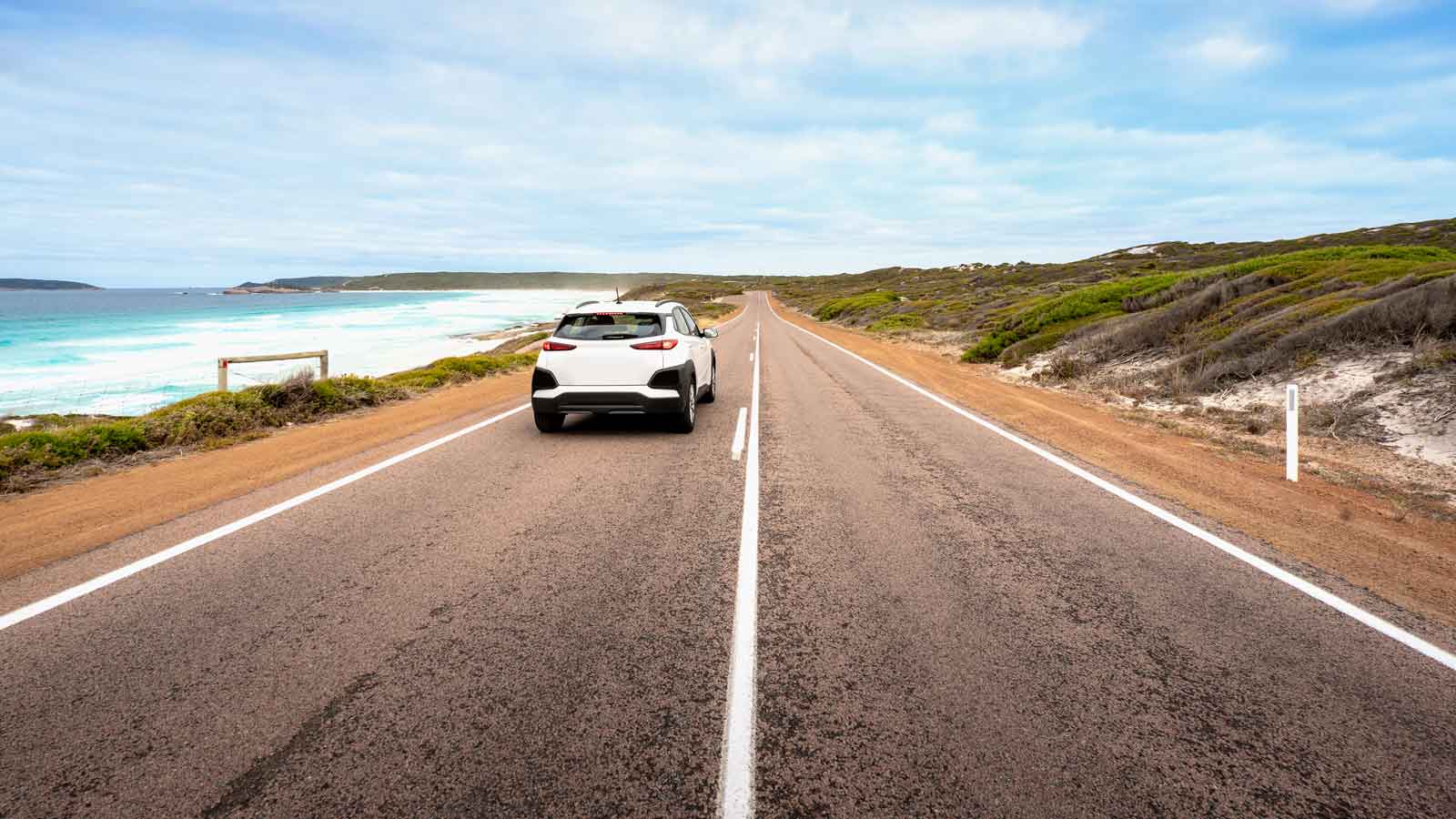 A white car driving on a costal road