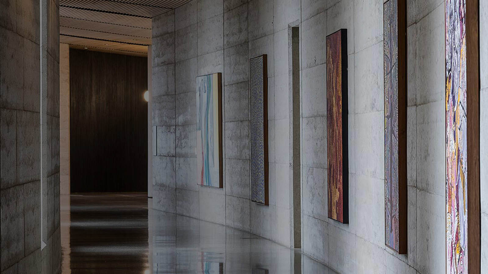 Image of an art-lined corridor with concrete walls at one of the RACV resorts.